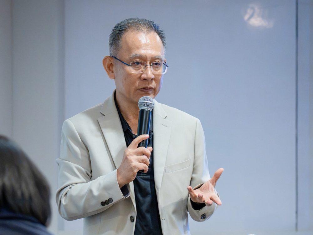 อ.ปกรณ์ วงศ์รัตนพิบูลย์ ถือไมค์บรรยายและอธิบายแนวทางการพัฒนาบุคลากรให้ผู้เข้าร่วม